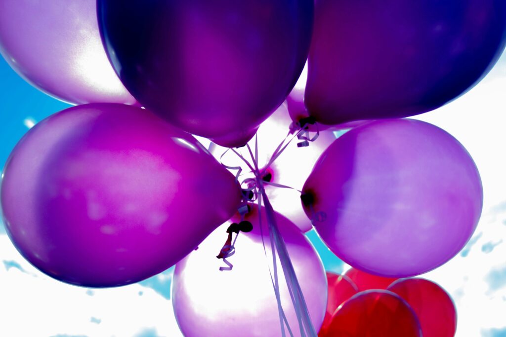 Bright purple balloons floating against a clear blue sky, perfect for celebrations.